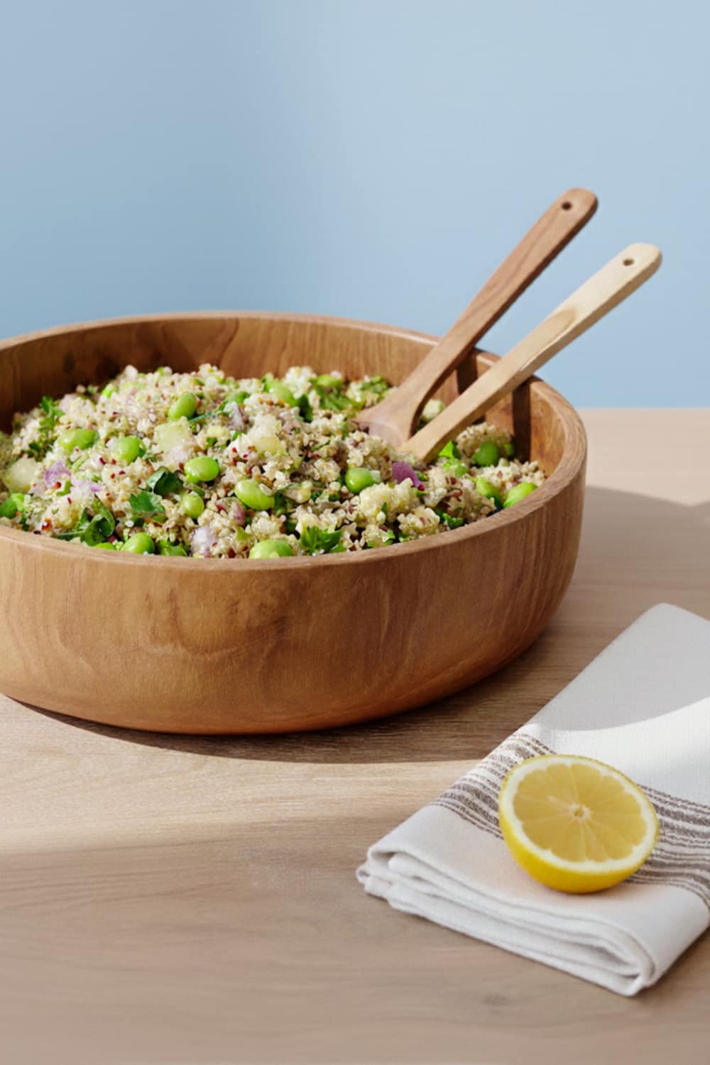 High-protein lemon edamame quinoa salad with fresh herbs in white bowl on marble surface